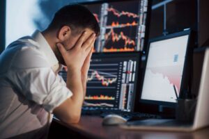A trader holding hands on his face while sitting at the desk
